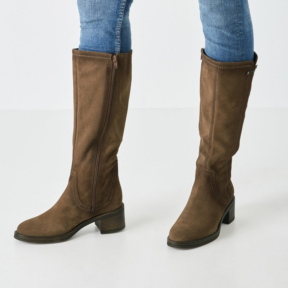 Brown knee-high boots with block heel and inner zip worn with blue jeans on a white background